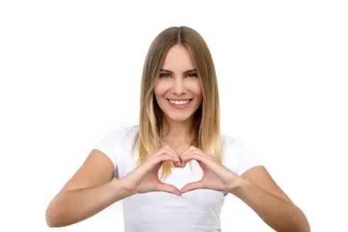 Vakker blond kvinne som smiler og danner et hjerte med hendene Vakker blond kvinne som smiler og danner et hjerte med hendene